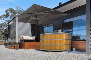 A modern building with a hot tub, outdoor seating, and a large umbrella. - Warrawindi Escapes (Penola)