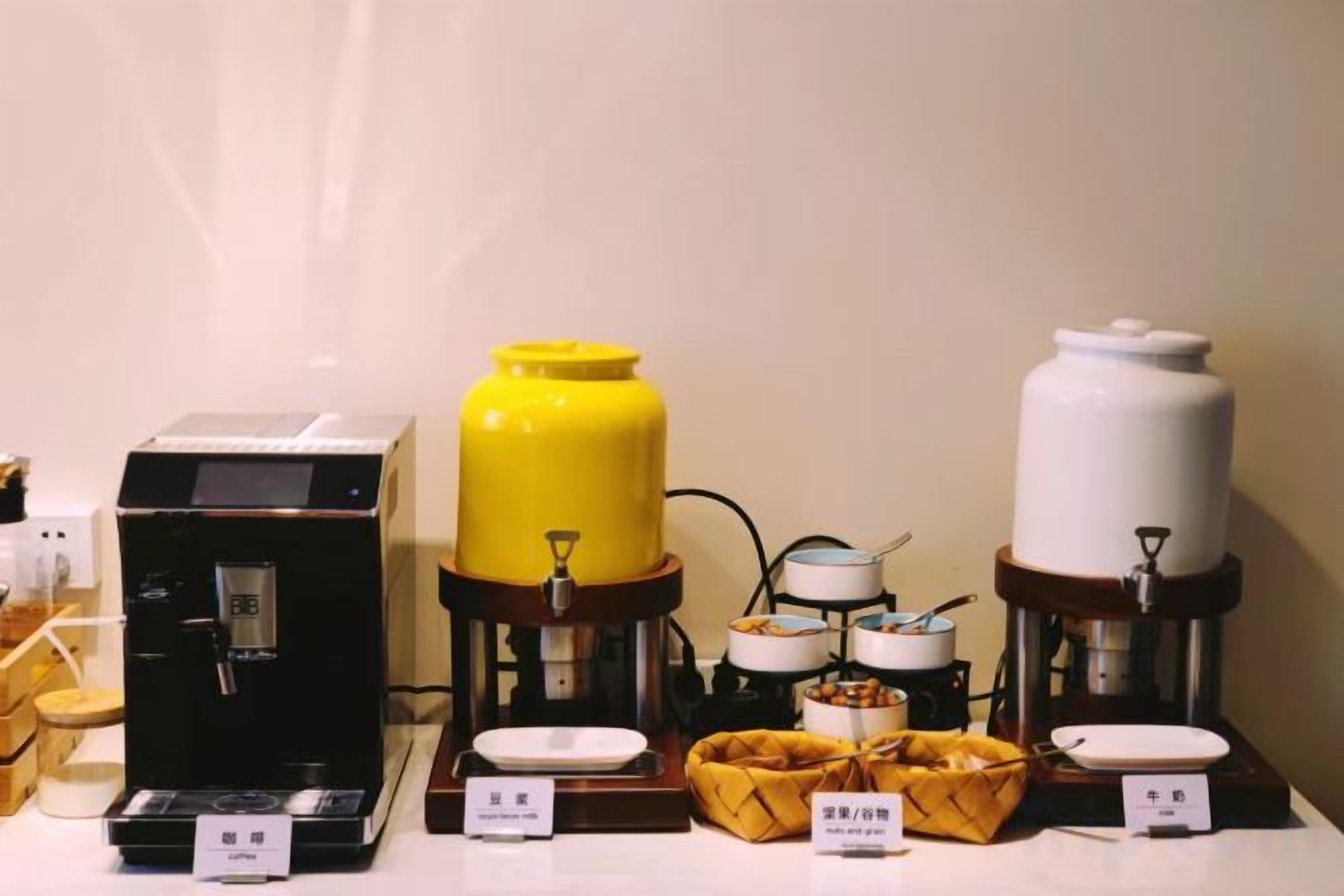 A coffee station with a coffee machine, a yellow water dispenser, and a white water dispenser.