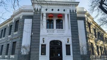 A classical building with a symmetrical facade, a central entrance with a black door, and two red lanterns above the entrance.