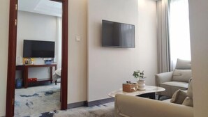 A modern living room with a sofa, a coffee table, a flat-screen TV, and a potted plant. - GreenTree Hotel (Beijing Xueqing Road Xuezhi Garden Subway Station) (Beijing)