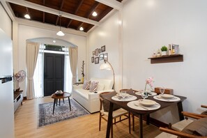 Un salon moderne avec un coin repas, comprenant un canapé, une table à manger pour deux personnes et une petite table d’appoint avec une lampe.