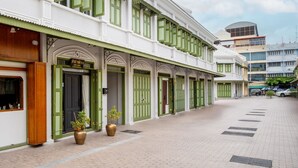 Een hotel in traditionele bouwstijl, met groene luiken en een betegelde looppad.