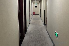 A hotel corridor with doors on both sides, a patterned carpet, and a green emergency exit sign. - Super 8 Hotel (Beijing Qianmen Zhushikou Subway Station) (Beijing)