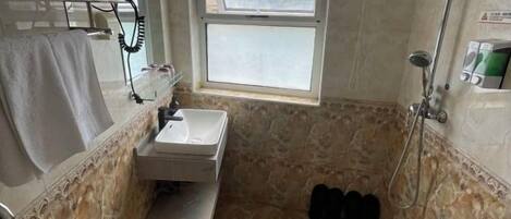 A bathroom with a sink, a window, and a shower.