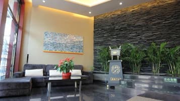 Un hall con sofá, mesa de centro, planta en maceta, pared de piedra y un pilar decorativo.