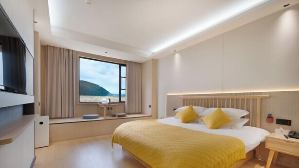 Una habitación de hotel moderna con una cama grande, una mesita de noche, un escritorio y vistas al exterior.