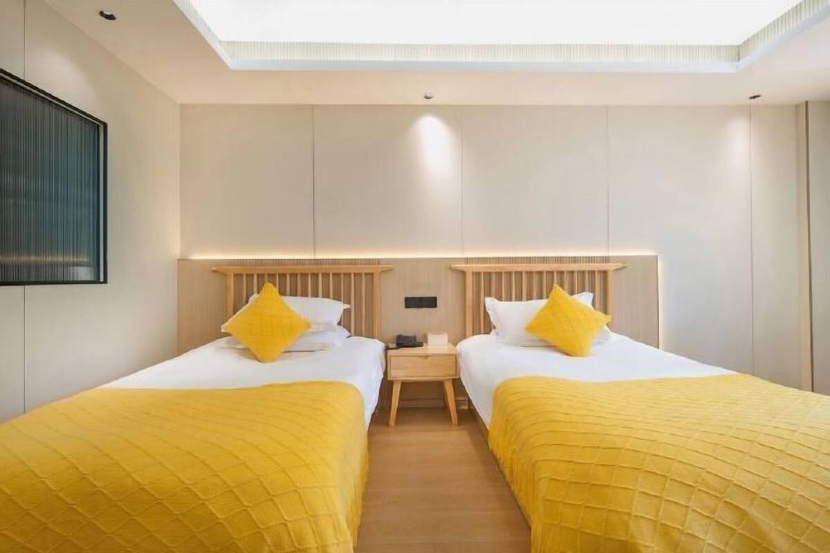 A hotel room with two beds, a nightstand, and a ceiling light.