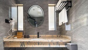 Un baño moderno con tocador de mármol, un espejo redondo, un perchero y un secador de pelo.