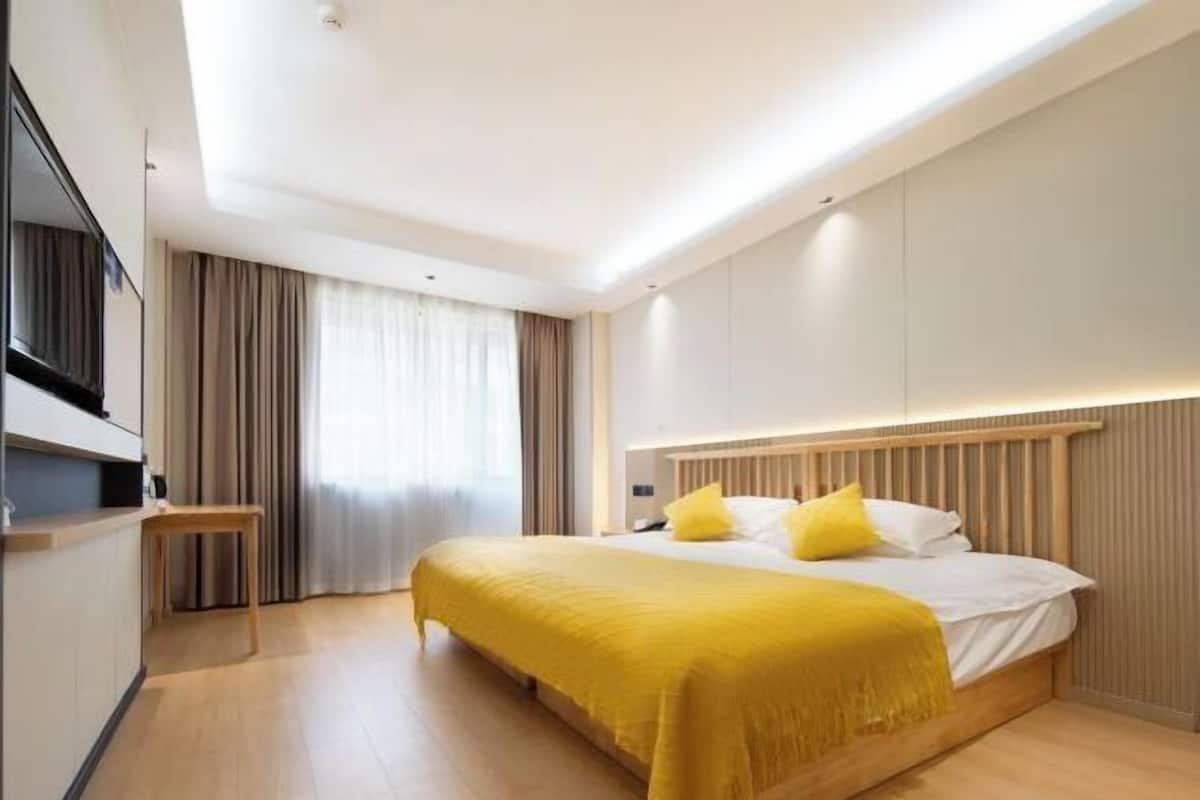 A modern hotel room with a large bed, a bedside table, and a built-in TV.