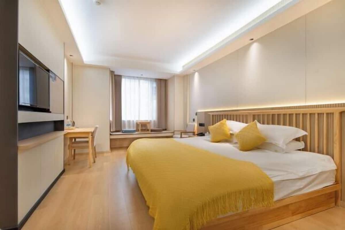 A hotel room with a bed, bedside table, and a television.