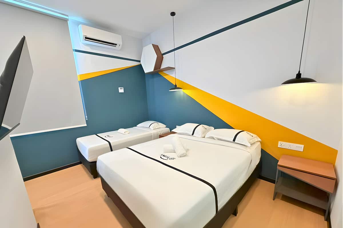 Camera d'albergo con due letti, un comodino, una lampada, un condizionatore d'aria e una mensola a muro.