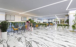 Un interior moderno con suelo de mármol, sillas amarillas y grises, y plantas verdes.