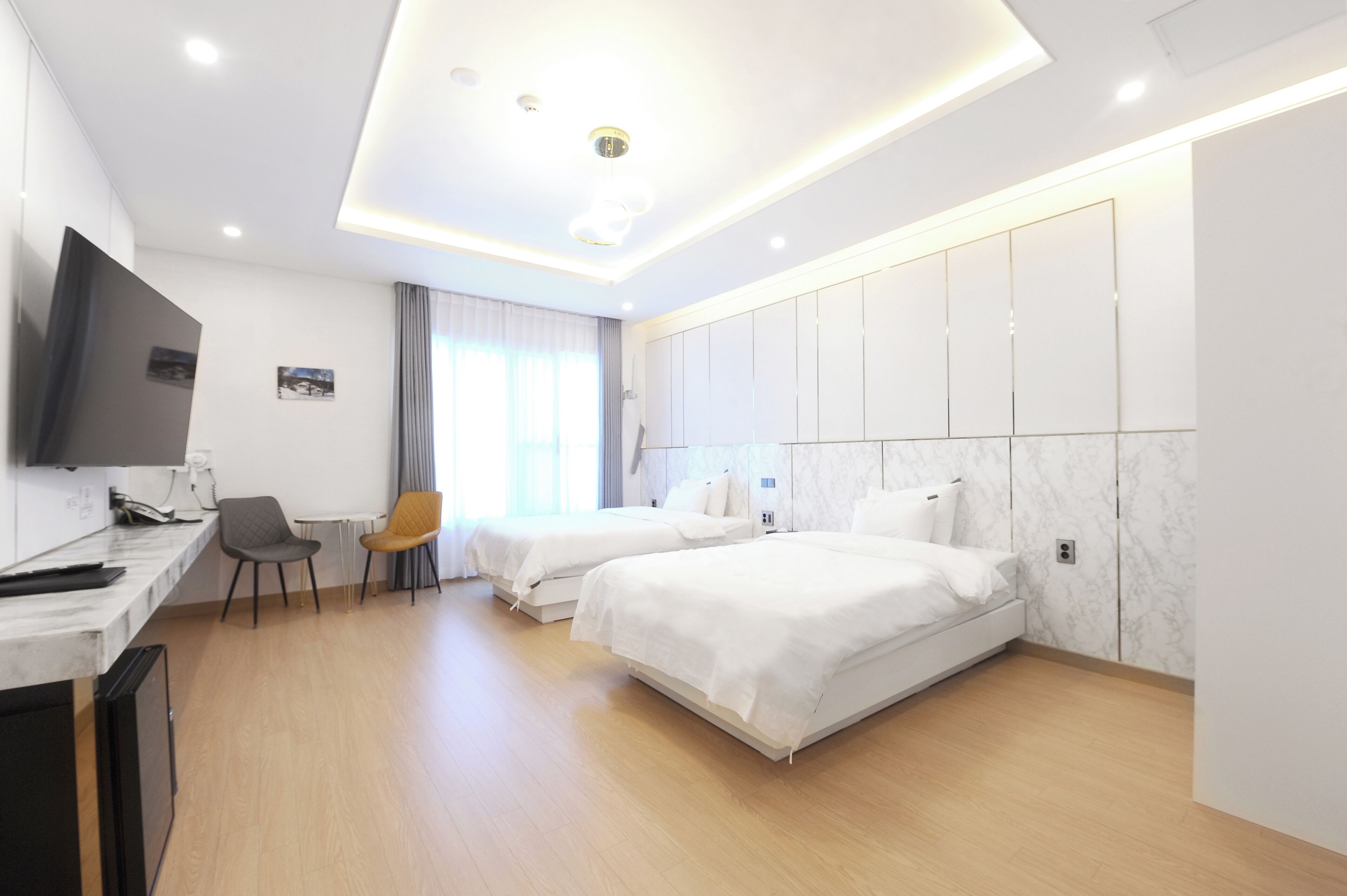 A modern hotel room with two beds, a desk, and a TV.