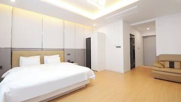 A modern hotel room with a large bed, a sofa, and a walk-in closet.