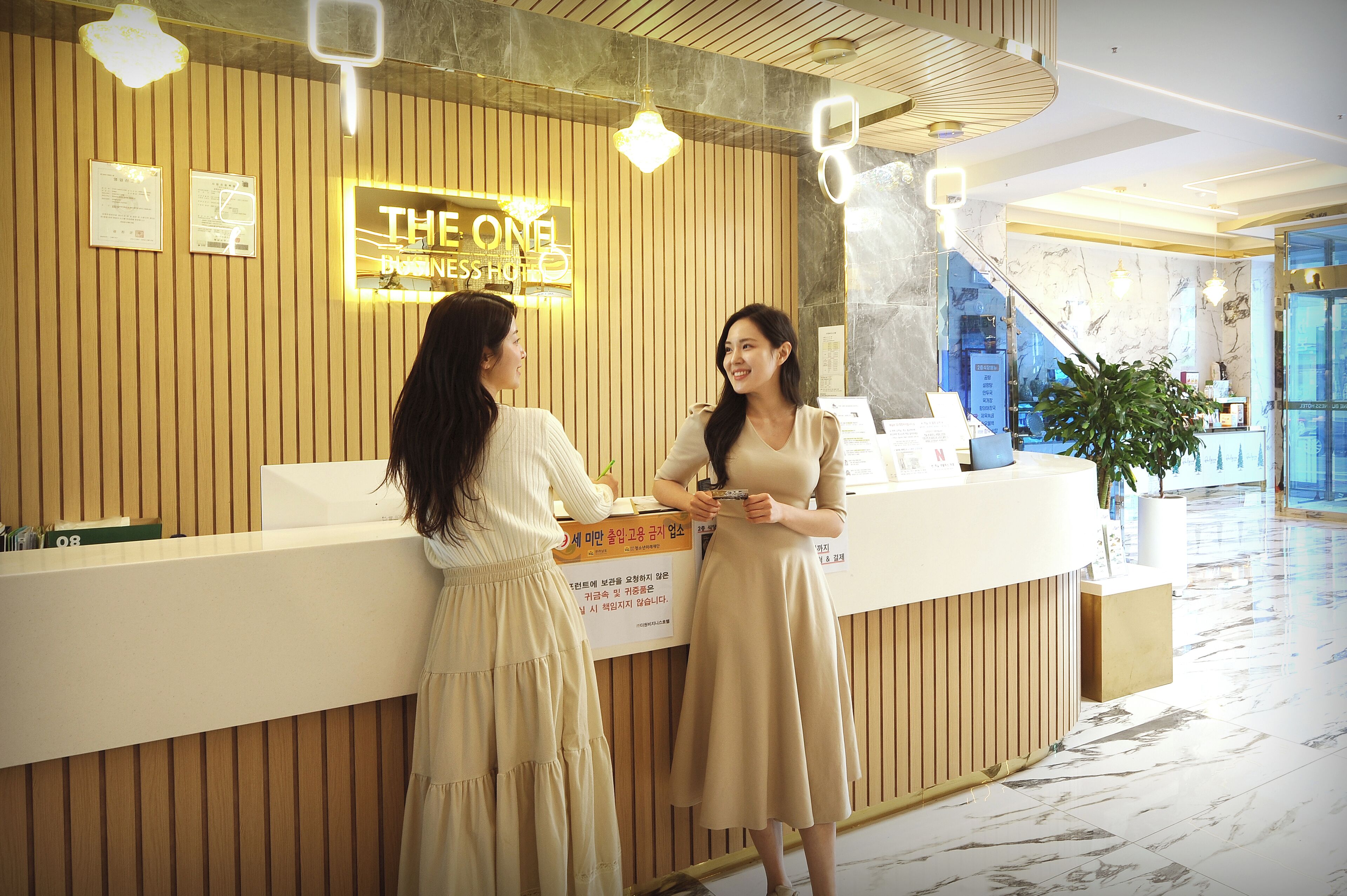 Un comptoir d’accueil avec une pancarte indiquant : « THE ONE BUSINESS hotel ».