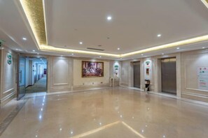 A spacious hotel lobby with a polished floor, a large wall-mounted TV, and an elevator. - Vienna International Hotel (Foshan Zemu Temple Metro Station Lingnan Xintiandi Branch) (Foshan)