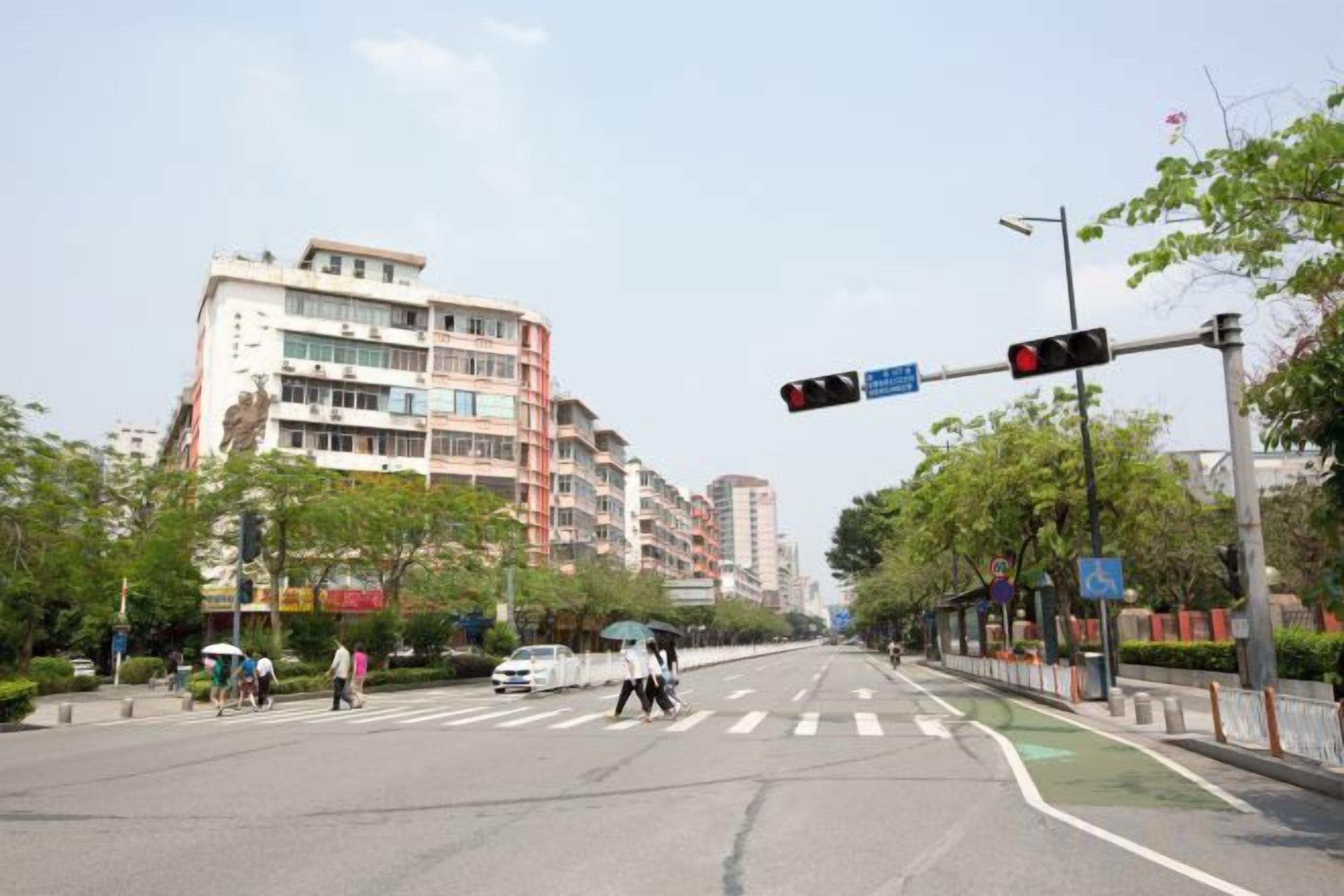 A multi-story building with a pedestrian crossing and traffic lights.