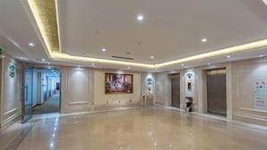 A spacious, well-lit hallway with a polished floor, a painting on the wall, and an elevator. - Vienna International Hotel (Foshan Shiwan Hotel Creative Industry Park Branch) (Foshan)