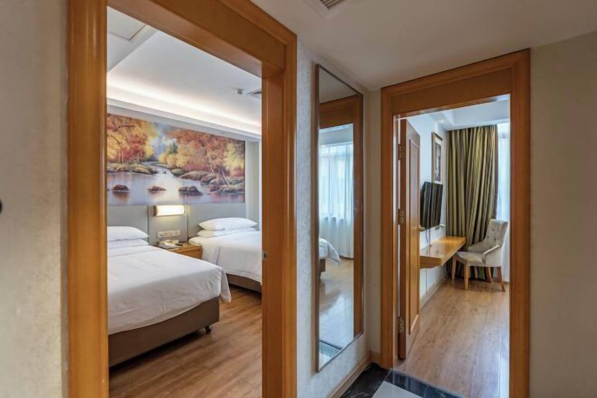 A hotel room with a bed, bedside tables, a desk, and a chair.