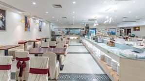 A restaurant with tables and chairs, a buffet area, and a counter with food items. - Vienna International Hotel (Foshan Shiwan Hotel Creative Industry Park Branch) (Foshan)
