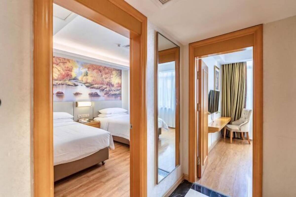 A hotel room with a bed, bedside tables, a desk, and a chair.