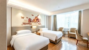 A hotel room with two beds, a mural on the wall, a small table, and a chair. - Vienna International Hotel (Foshan Shiwan Hotel Creative Industry Park Branch) (Foshan)