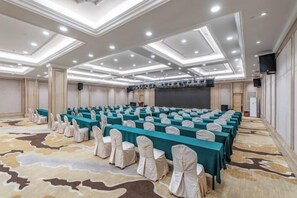 A conference room with rows of tables and chairs, a stage, and a carpeted floor. - Vienna International Hotel (Foshan Zemu Temple Metro Station Lingnan Xintiandi Branch) (Foshan)