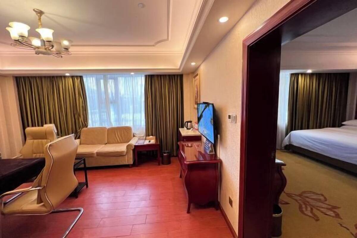 A hotel room with a sofa, a desk, a television, and a bed.