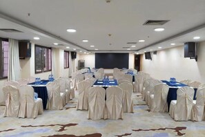 Une salle de conférence équipée de tables rondes, de chaises et d’un écran de projection.