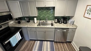A modern kitchen with white cabinets, a stainless steel sink, a microwave, and a coffee maker.