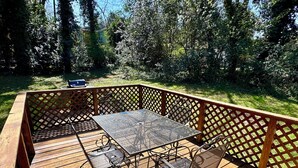 A wooden deck with a metal table and chairs, surrounded by a wooden lattice fence.