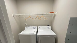 A laundry room with two front-loading washing machines and a drying rack above. - Charming 2-bedroom apartment in Wilmington, NC (Wilmington)