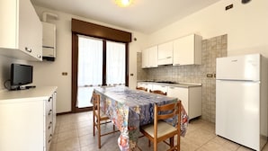 A compact kitchen with white cabinets, a tiled backsplash, a built-in oven, and a refrigerator.