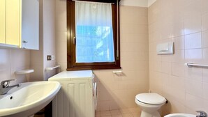 Un baño pequeño con un lavabo blanco, un inodoro y una lavadora.