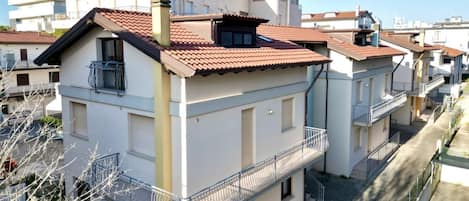 Un edificio residencial de varios pisos, con balcones, techo de tejas y cielo despejado.