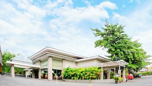 Un hôtel moderne doté d’une entrée couverte, de grandes fenêtres et d’un jardin luxuriant.