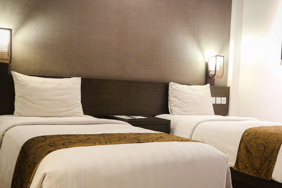 Ein Hotelzimmer mit zwei Betten, einem Nachttisch und einer Wandleuchte.