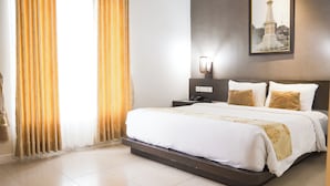 Une chambre d’hôtel avec un grand lit, une table de chevet, une lampe fixée au mur et un tableau représentant un phare.
