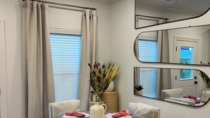 A dining area with a round table, four chairs, a vase with flowers, and a mirror on the wall. - 3 Bedroom NEW CONDO MINUTES FROM Ole Miss Campus, The Square, and the Grove!! (Oxford)