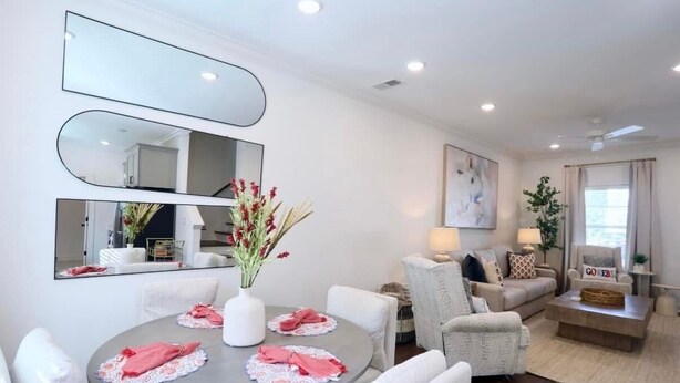 A modern living room with a dining area, white furniture, a large mirror, and a vase with flowers. - 3 Bedroom NEW CONDO MINUTES FROM Ole Miss Campus, The Square, and the Grove!! (Oxford)