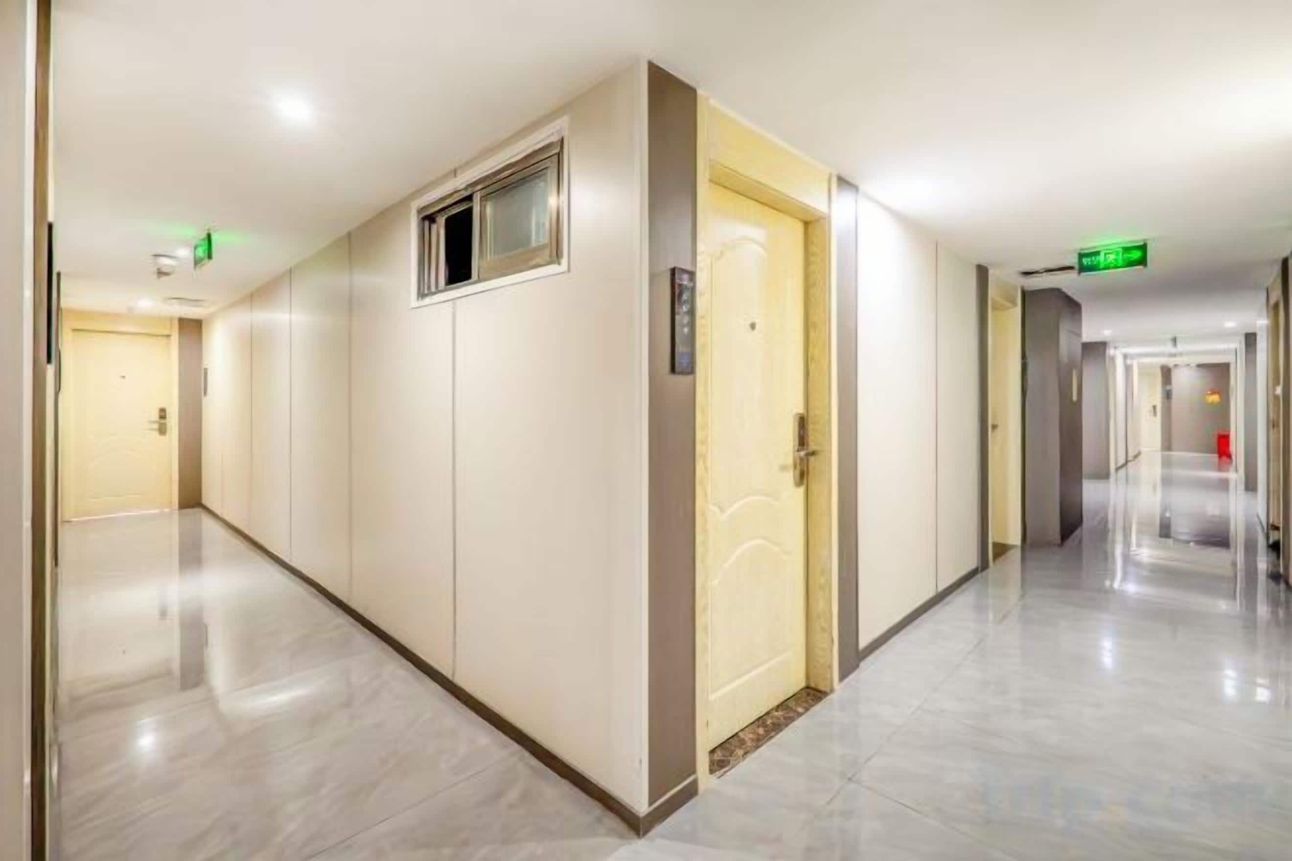 A hotel corridor with doors, a fire alarm, and a clean floor.