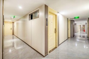 A hotel corridor with doors, a fire alarm, and a clean floor. - Tiantian Chain Hotel Chongqing Xinan Hospital (Chongqing)
