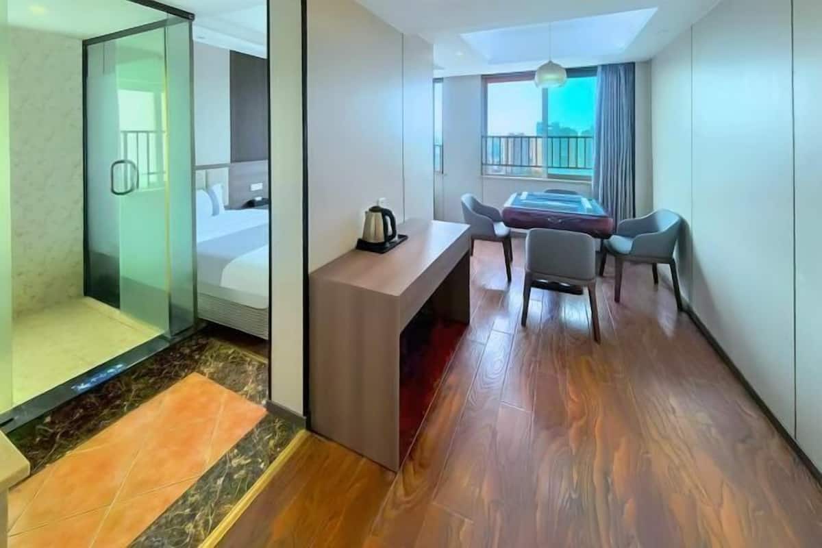 A hotel room with a bed, a desk, a chair, a shower, and a balcony with a view.