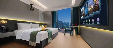 A modern hotel room with a large bed, a city view, a digital art display, and a small table with a lamp.