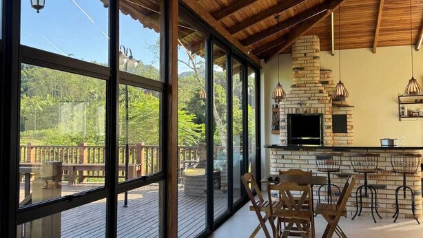 A spacious room with large windows, a wooden ceiling, and a brick fireplace.