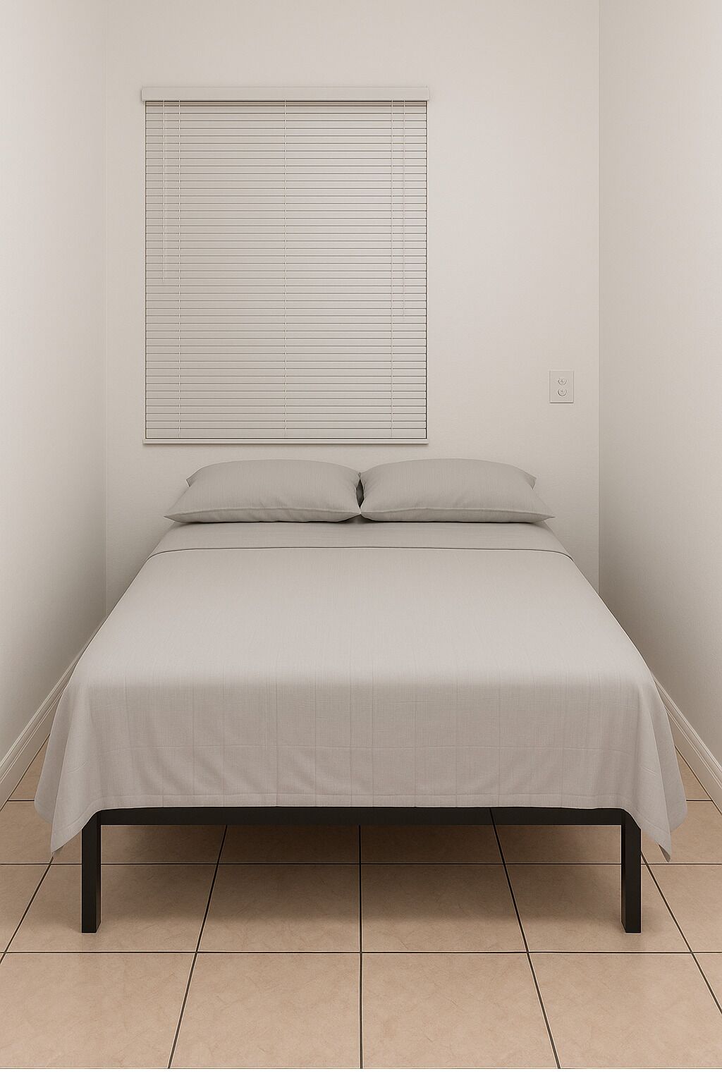 A simple, unadorned bed in a room with a plain wall and a window with horizontal blinds.