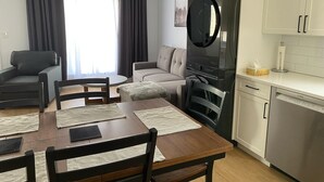 Una sala de estar moderna con una mesa de comedor, sillas, un sofá y una cocina equipada con lavavajillas Bosch.