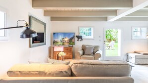 Ett vardagsrum med en soffa, en tv, en lampa och en tavla på väggen.