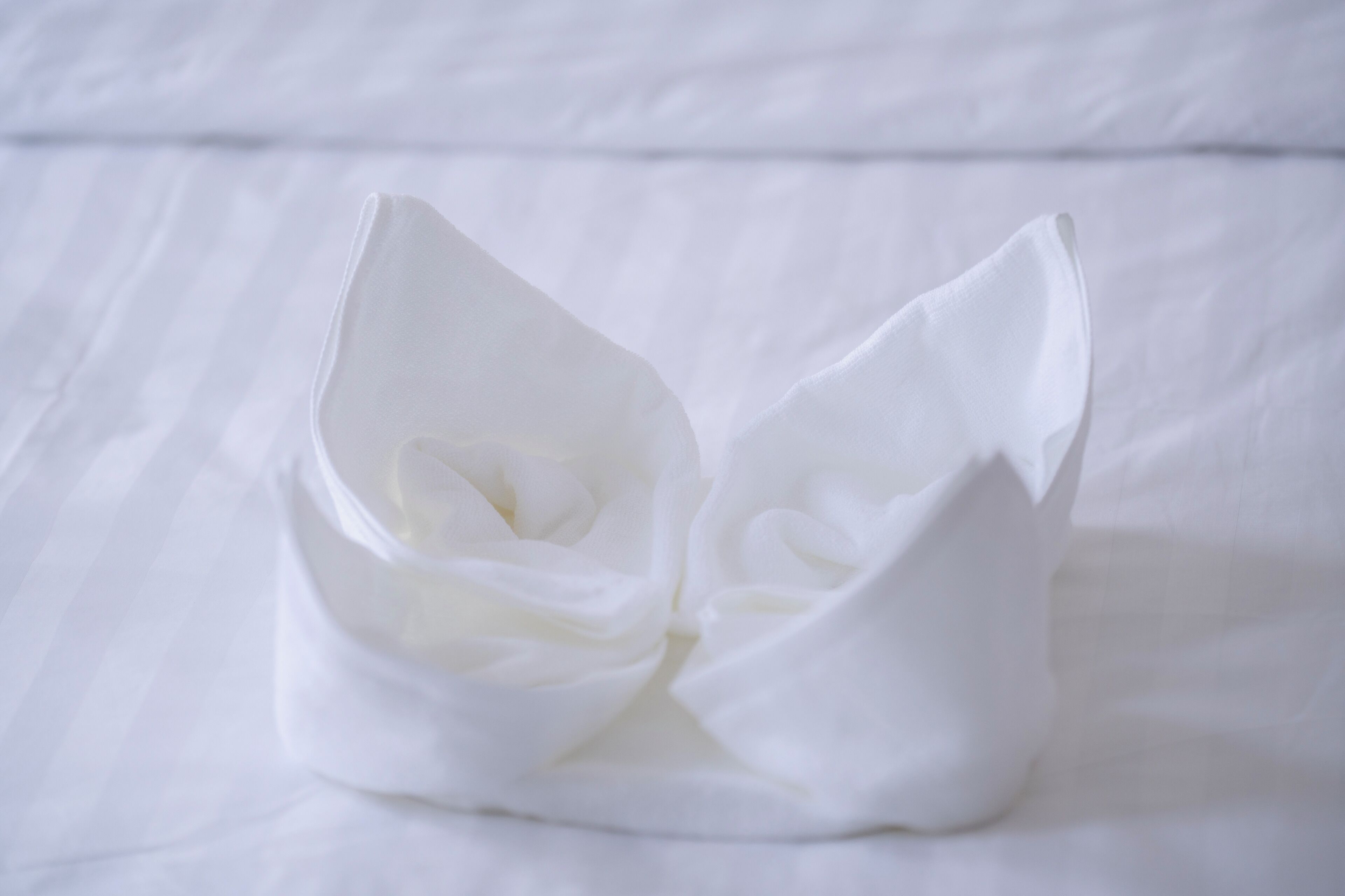 A white, folded fabric object on a white surface.