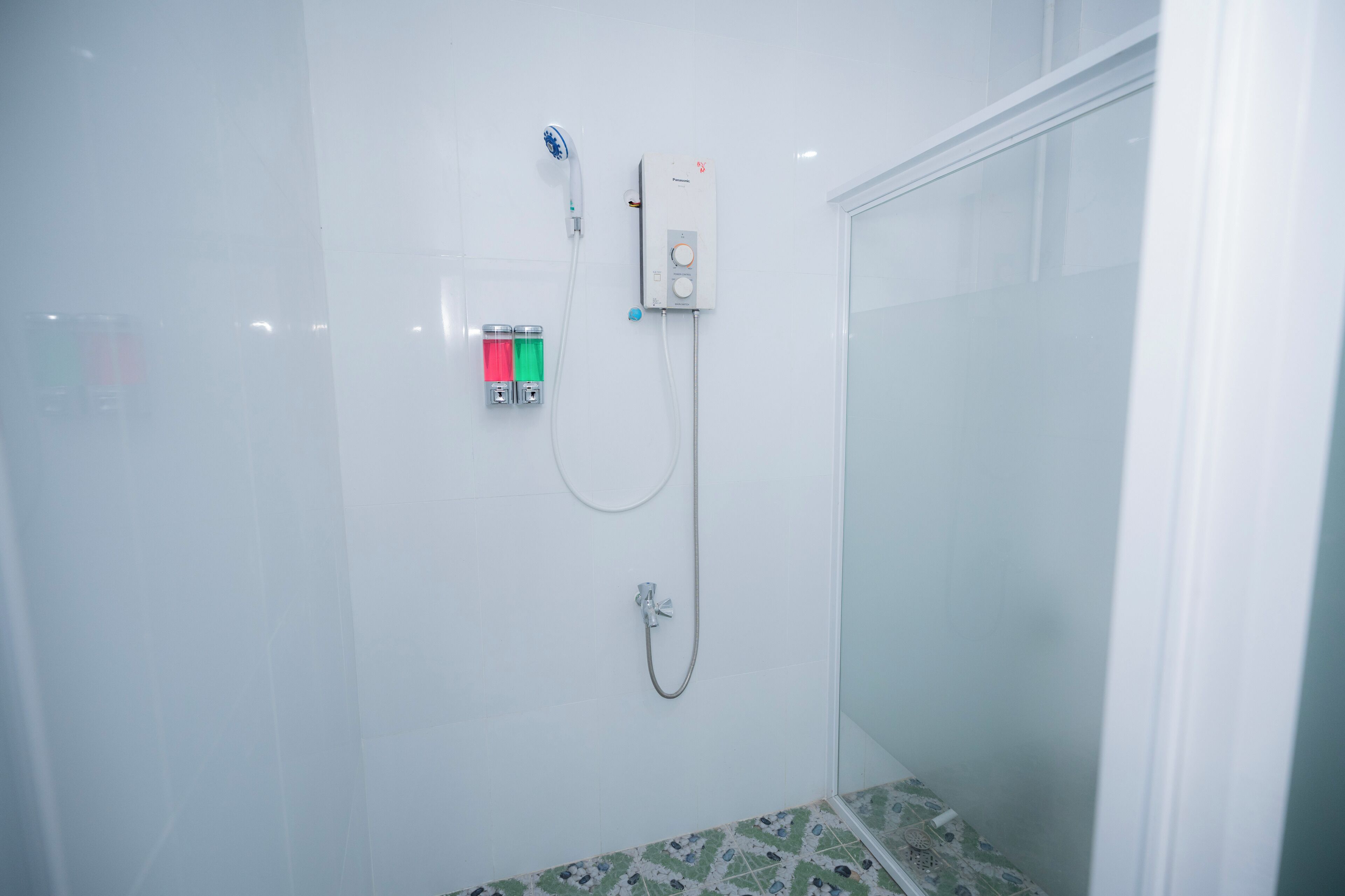 A shower with a handheld showerhead, a wall-mounted control panel, and a glass-enclosed shower stall.